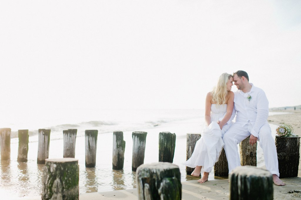 Photo Brautpaar sitzt verträumt auf Strandpflöcken